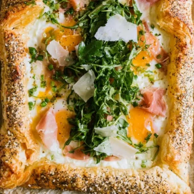 Baked prosciutto and egg breakfast tart served on a white plate