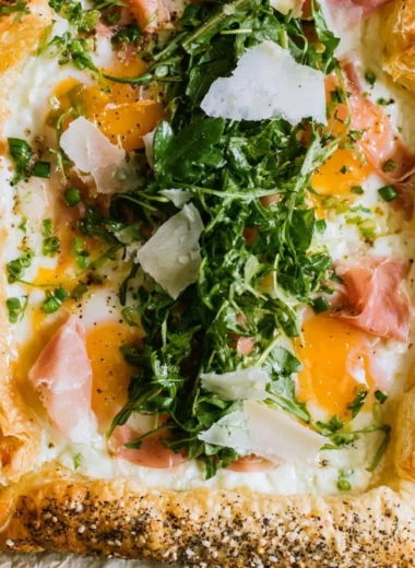 Baked prosciutto and egg breakfast tart served on a white plate