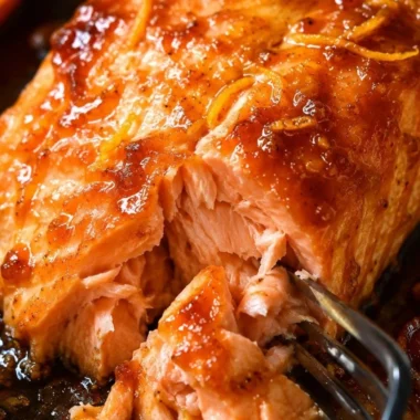 Baked salmon fillet topped with vibrant orange sauce, garnished with herbs