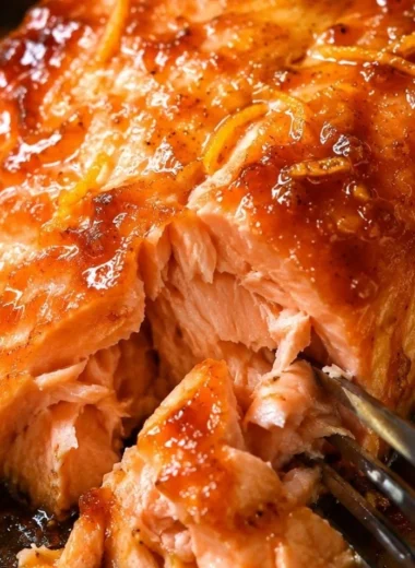 Baked salmon fillet topped with vibrant orange sauce, garnished with herbs