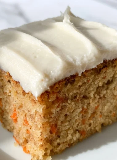 Dairy-free carrot cake with cream frosting on a rustic wooden table