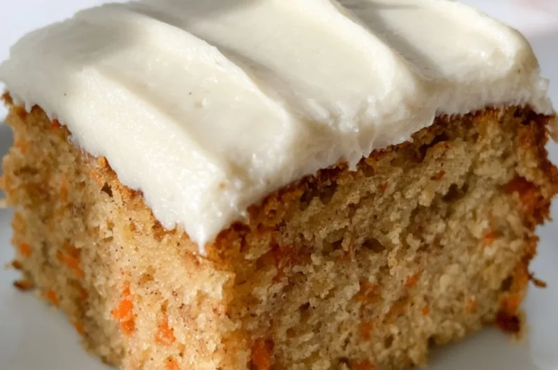 Dairy-free carrot cake with cream frosting on a rustic wooden table