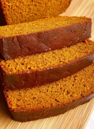 Homemade easy pumpkin bread loaf displayed on a wooden table.