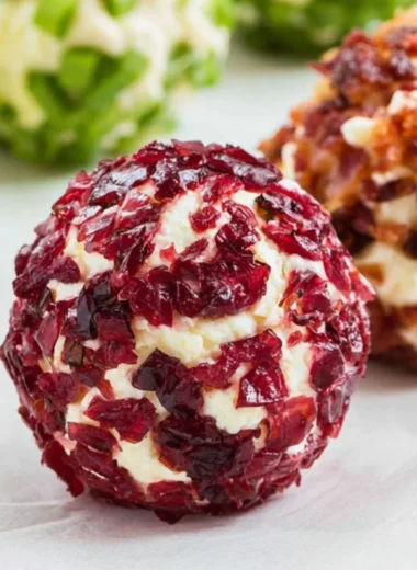 A platter of mini cheeseball bites topped with herbs and spices.