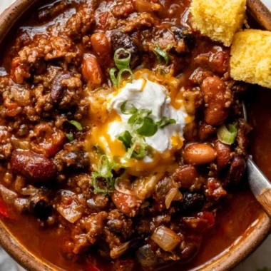 Bowl of delicious chili topped with cheese and herbs