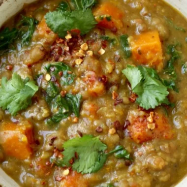 Bowl of earthy Moroccan sweet potato lentil stew with spices and fresh herbs.