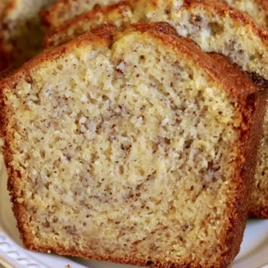 Loaf of perfect banana bread with sliced bananas on a wooden table