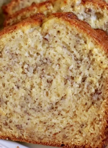 Loaf of perfect banana bread with sliced bananas on a wooden table