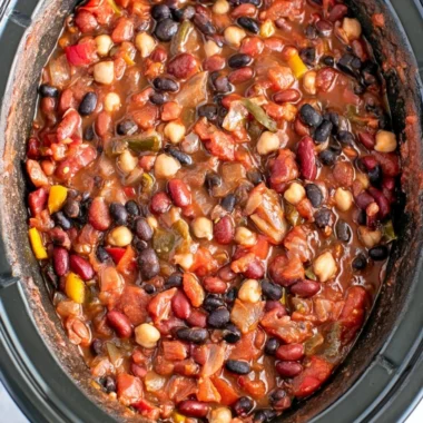 A bowl of slow cooker vegetarian chili topped with fresh herbs and served with bread.