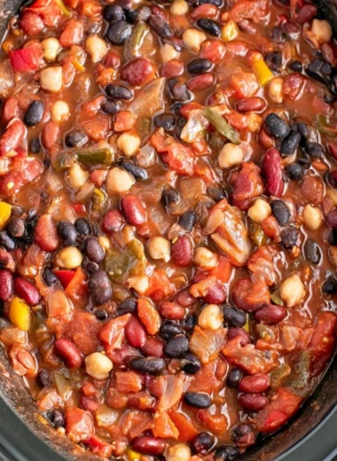 A bowl of slow cooker vegetarian chili topped with fresh herbs and served with bread.