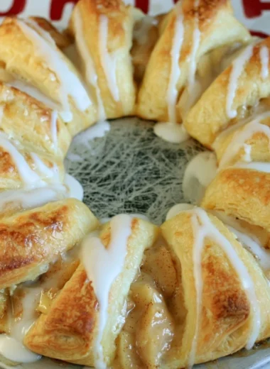 Freshly baked Apple Crescent Ring topped with sugar glaze on a white plate.