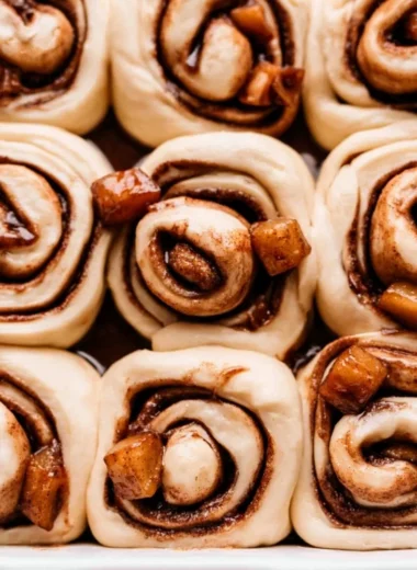 Freshly baked apple pie cinnamon rolls with a drizzle of icing on top