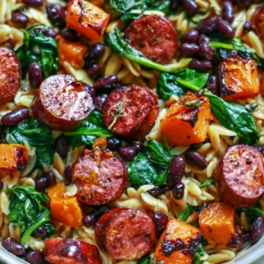 Butternut squash orzo with black beans, sausage, and spinach, served in a bowl.