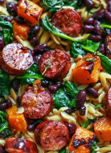 Butternut squash orzo with black beans, sausage, and spinach, served in a bowl.