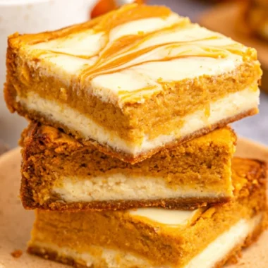 Delicious Pumpkin Cream Cheese Cheesecake Bars topped with whipped cream.
