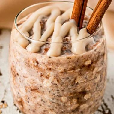 Bowl of cinnamon roll overnight oats topped with cinnamon and nuts.