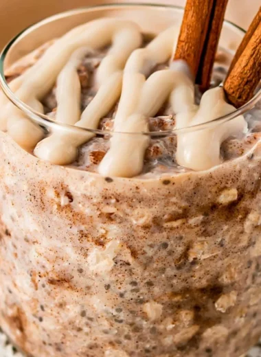 Bowl of cinnamon roll overnight oats topped with cinnamon and nuts.