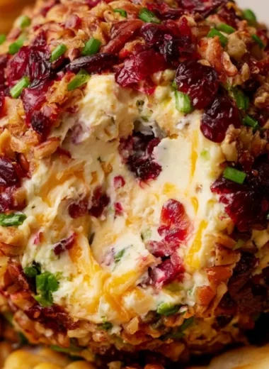 Cranberry pecan cheese ball served on a wooden platter with crackers