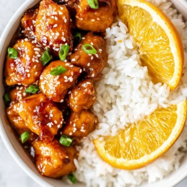Healthy orange chicken served in a bowl with vegetables and orange slices