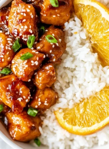 Healthy orange chicken served in a bowl with vegetables and orange slices