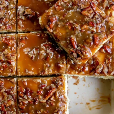 Pecan pie cheesecake bars topped with pecans and caramel drizzle
