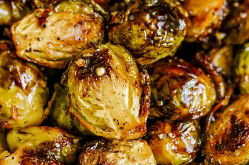 Plate of roasted Brussels sprouts with honey balsamic sauce drizzled on top.