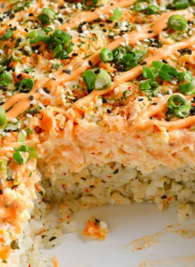 Baked Salmon Sushi served in a casserole dish with fresh ingredients and toppings.