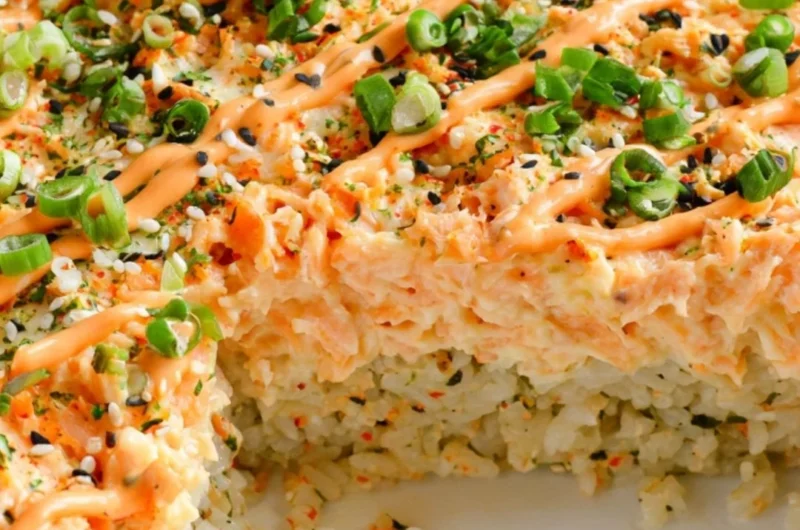 Baked Salmon Sushi served in a casserole dish with fresh ingredients and toppings.