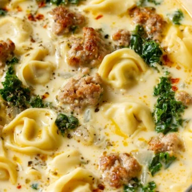 Bowl of delicious Sausage Tortellini Soup with herbs and cheese.
