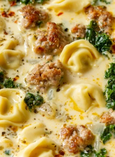 Bowl of delicious Sausage Tortellini Soup with herbs and cheese.